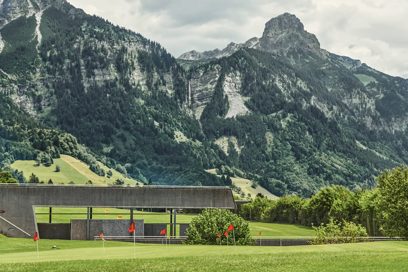 Driving Range mit überdachten Abschlägen vor der Bergkulisse
