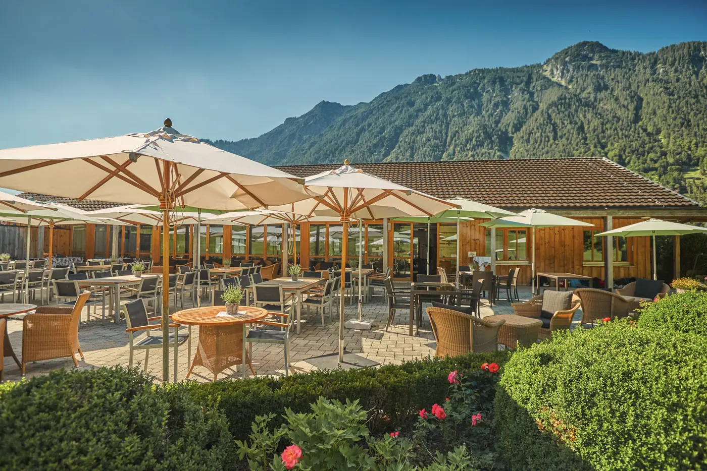 Panoramaterrasse des Clubrestaurants mit Sonnenschirmen und Bergblick